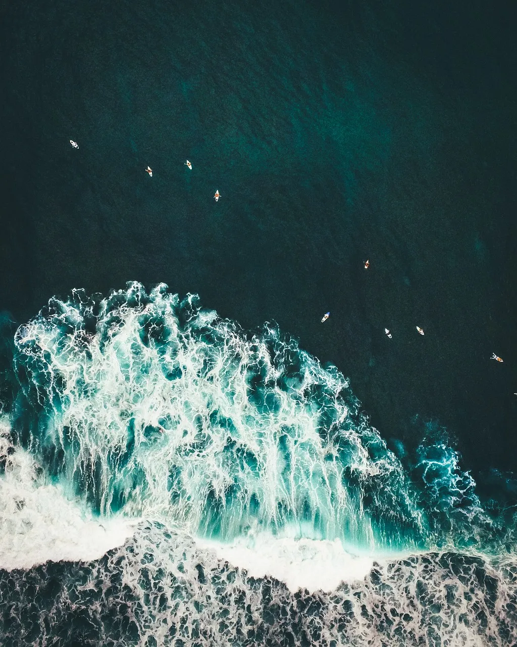 A drone shot looking down at several surfers waiting for a wave.