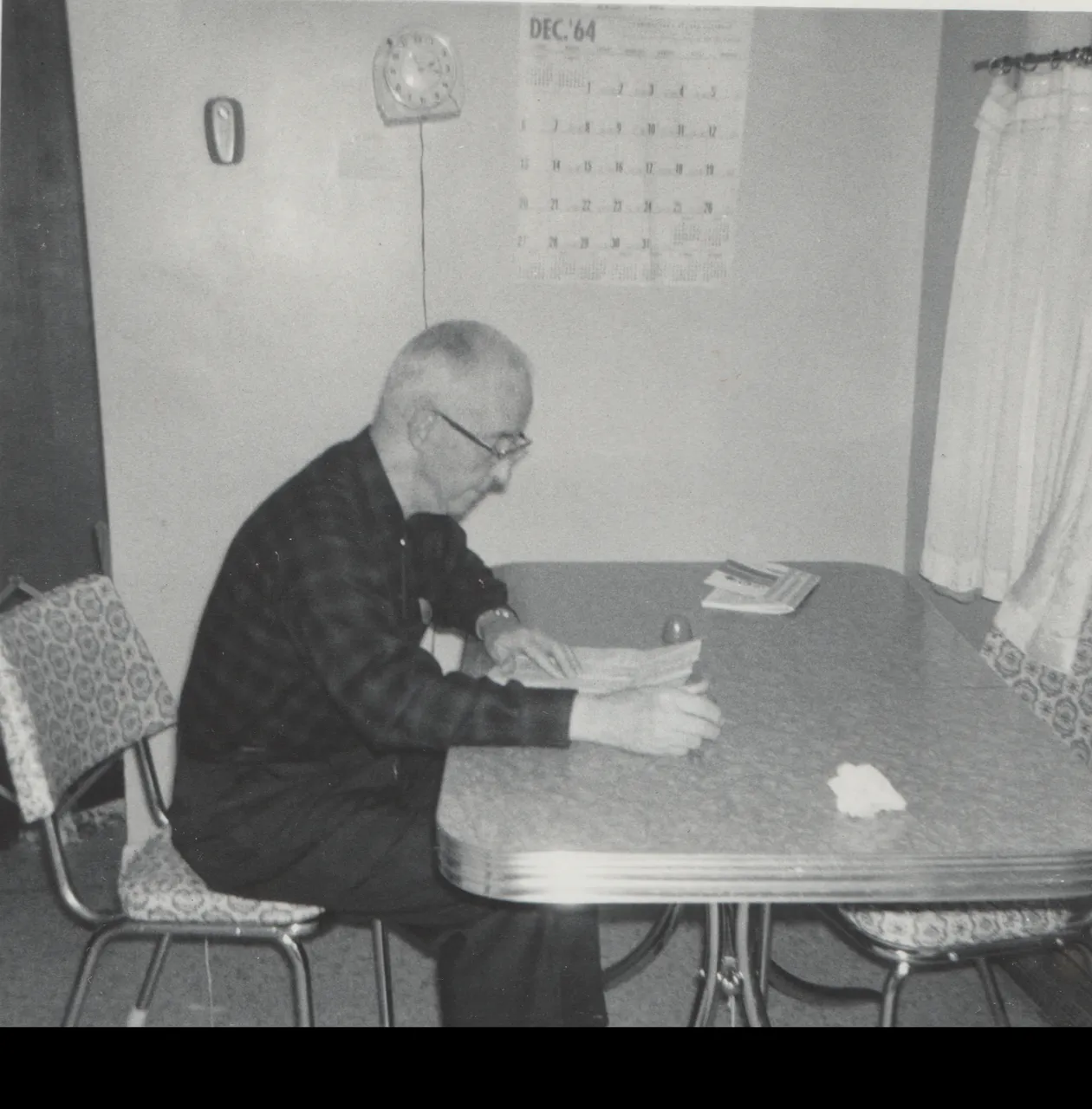 1964-12 - Charles Dwight Pickett, sitting on a chair at a kitchen table or something in black and white, calendar says Dec 64 but was developed in Feb 1965, 1pic.png