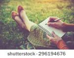 stock-photo-female-hands-with-pen-writing-on-notebook-on-grass-outside-296194676.jpg