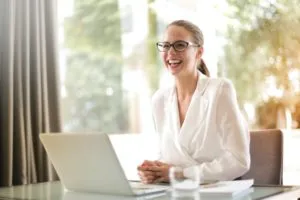 giovane donna professionista che sorride alla postazione di lavoro presumibilmente nell'ambito del project management