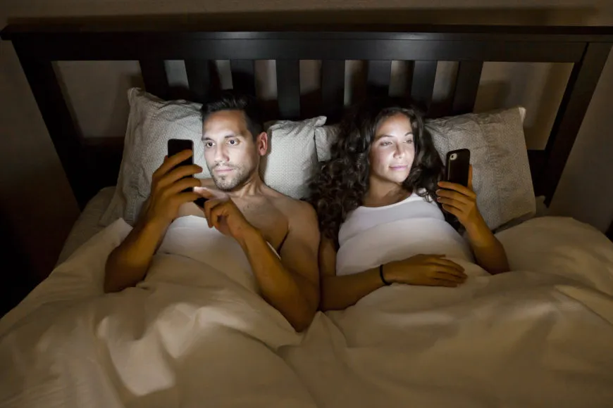 couple-looking-at-phones-in-bed-870x580.jpg