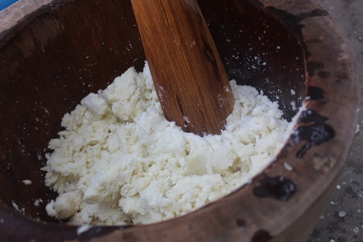 The boiled yam being pounded in a mortar using a pestle.