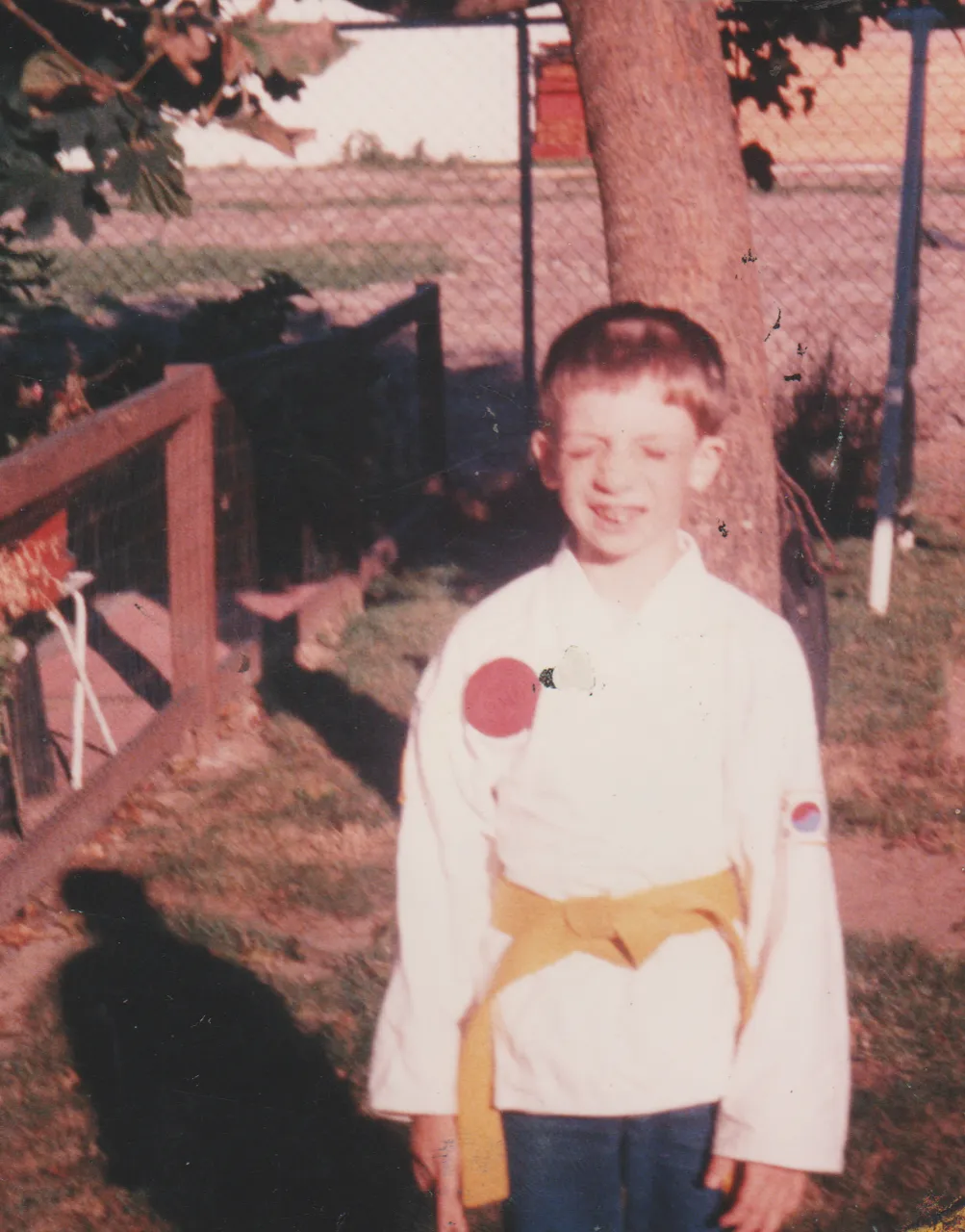 1990-06 - Rick Arnold as a yellow belt, apx date, probably before 1992, looks like during the summer, 163 front yard, big tree.png