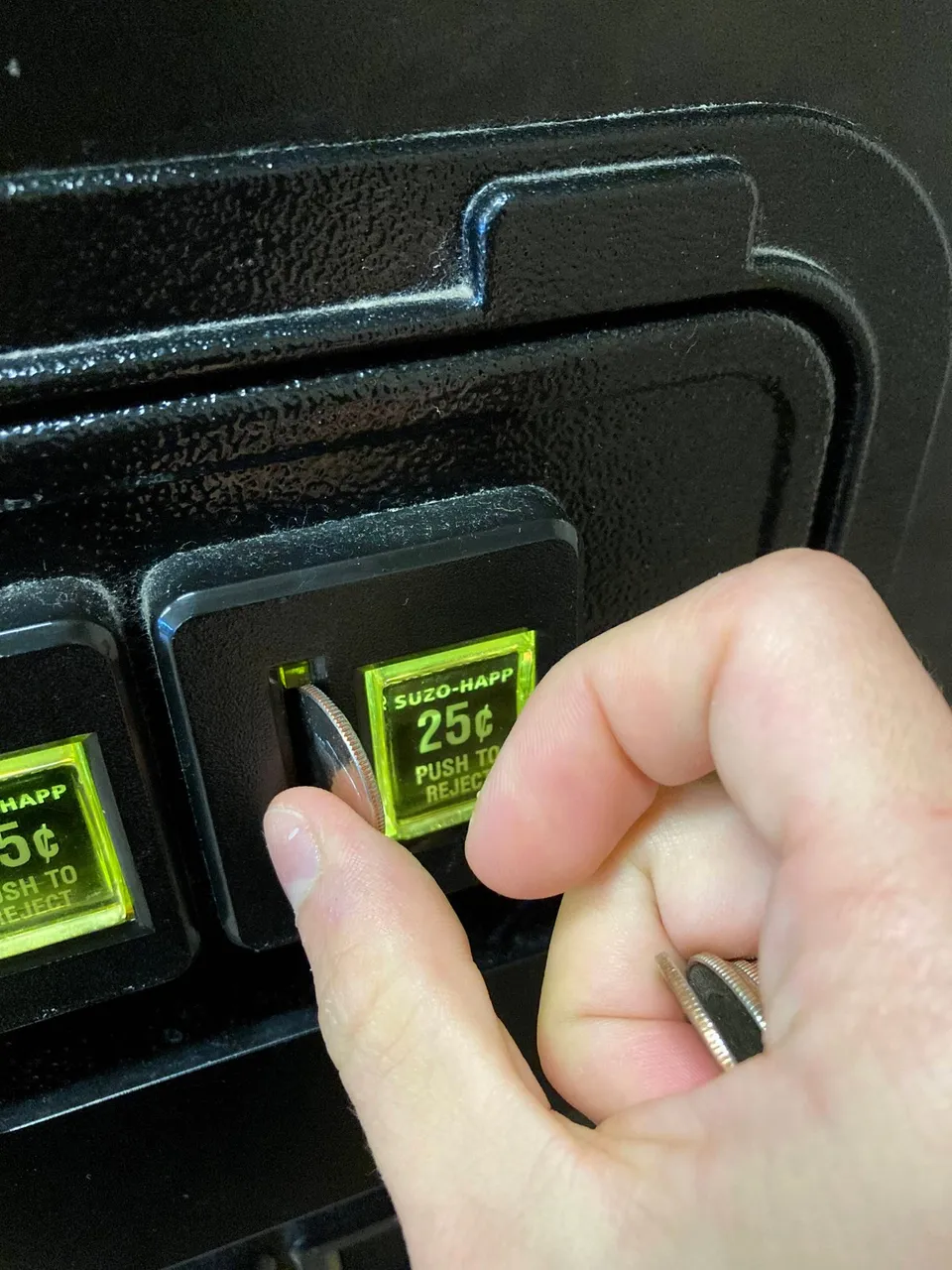 Public domain stock image of a person's hand putting quarters into a payment slot