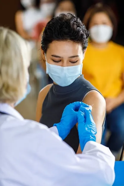 retrato-primer-plano-paciente-usa-mascarilla-sentarse-mirar-camara-mientras-esta-cola-vacunacion-recibir-inyeccion-vacuna-disparada-medico-bata-laboratorio-blanca-guantes-goma-azules_102814-396(1).jpg