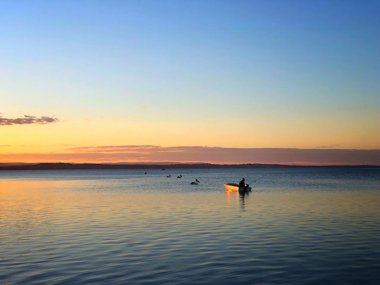 Fisherman on a boat on Tuggerah Lake, The Entrance, NSW