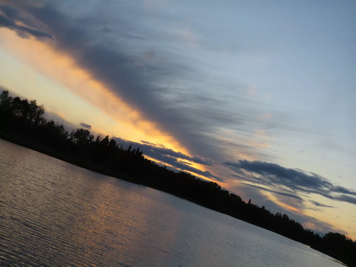 looking down pond with streak of clouds above lined with colors of sunset.JPG