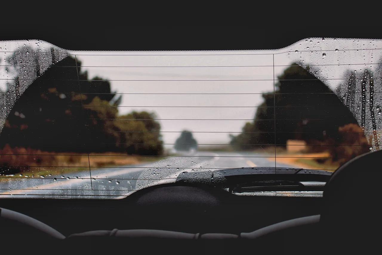 View though rear window of car in rain. Photo by Devon Janse van Rensburg via Unsplash.com