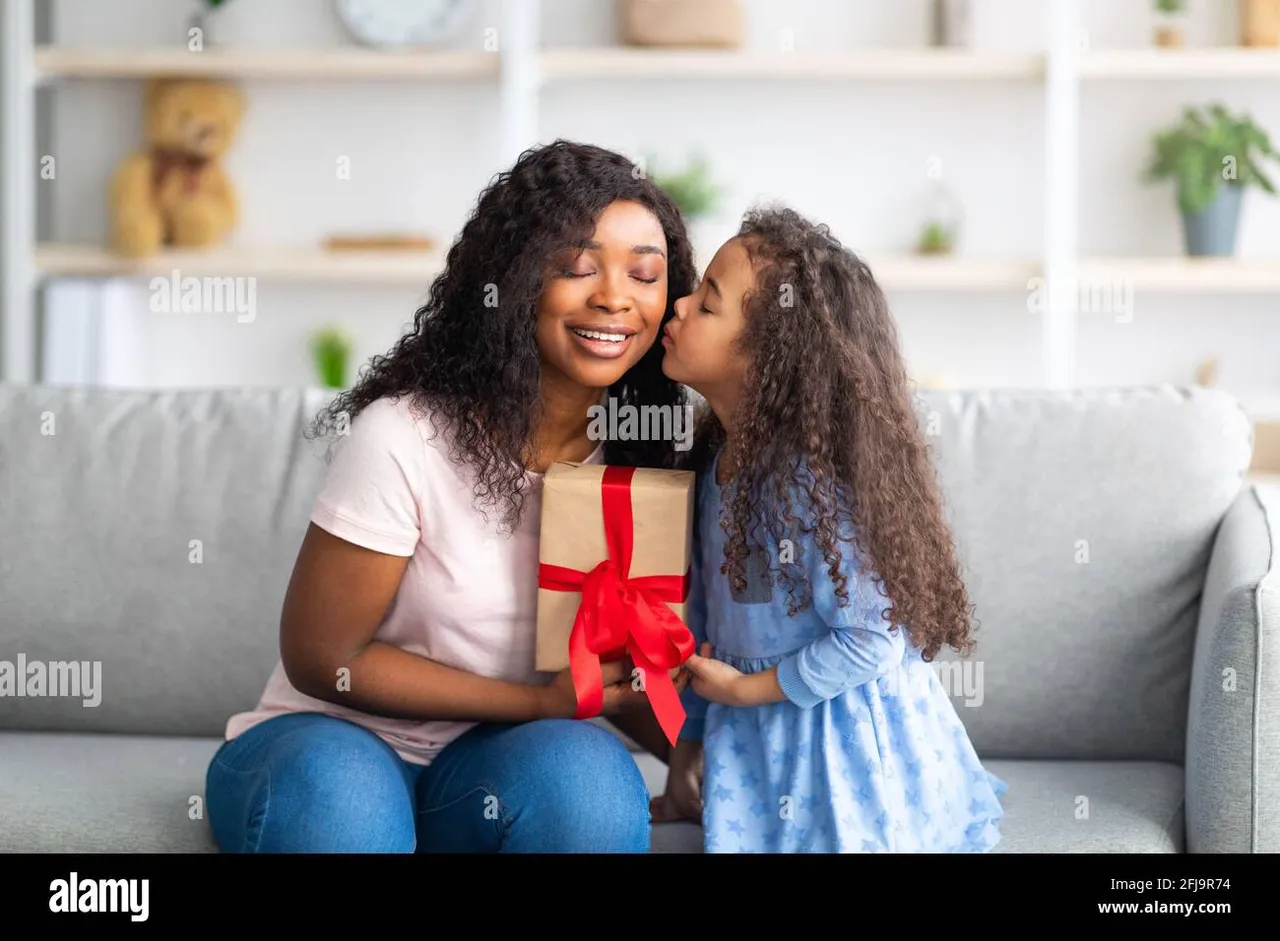 mothers-day-celebration-lovely-little-black-girl-giving-mom-wrapped-holiday-gift-and-kissing-her-on-cheek-at-home-2FJ9R74.jpg