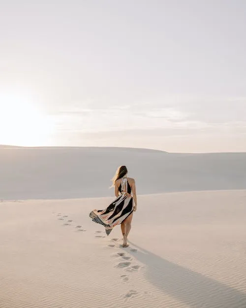 Free Woman in Dress Walking in Sand Dunes Stock Photo