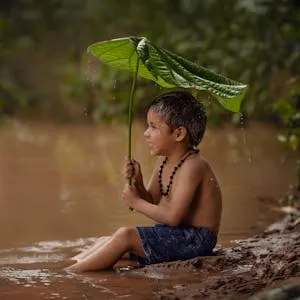 free-photo-of-boy-sitting-in-water-and-holding-big-leaf-over-head.jpeg
