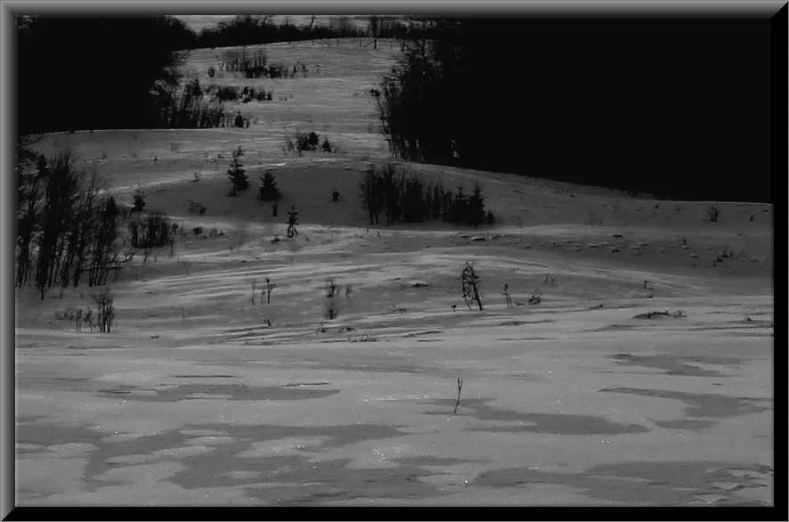 patterns on windswept snow on hill leading to frozen lake.JPG