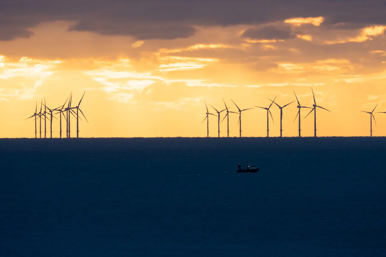 Shot of the Rampion Wind Farm at sunset with a small boat in the foreground