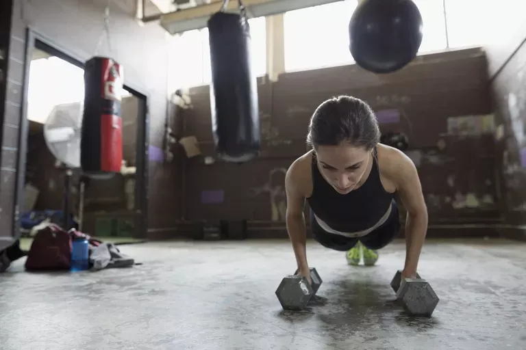 strong-female-boxer-doing-plank-exercise-with-dumbbells-at-gym-728760769-5b3567dcc9e77c00379c8c17.jpg