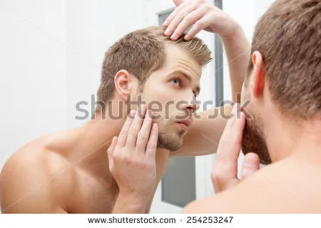 stock-photo-man-standing-in-front-of-mirror-worrying-about-hair-loss-254253247.jpg