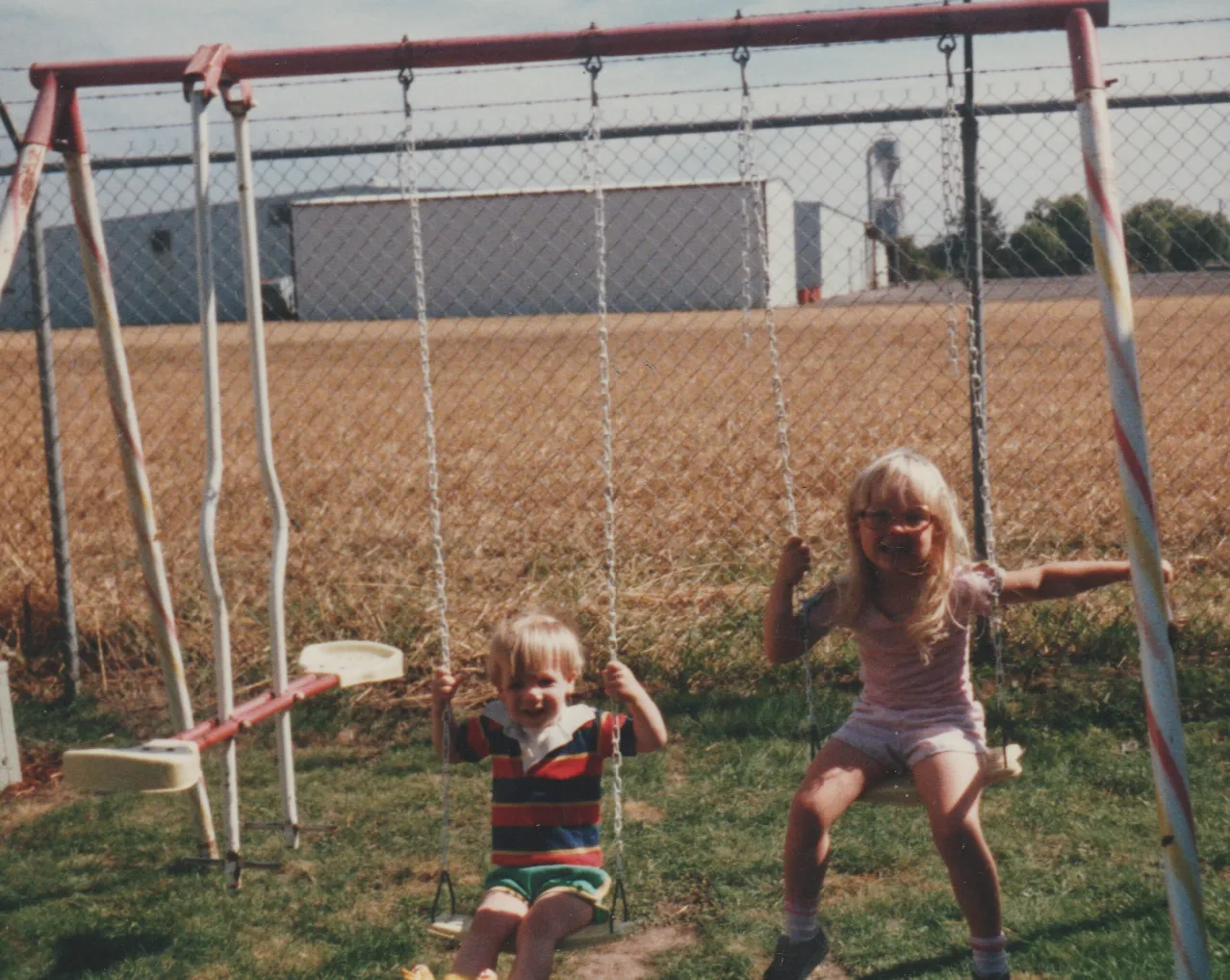 1984-07 - Summer of 1984 - Katie, Ricky, 163 front yard, swing, fun, behind big tree by the fence and field CROPPED.png