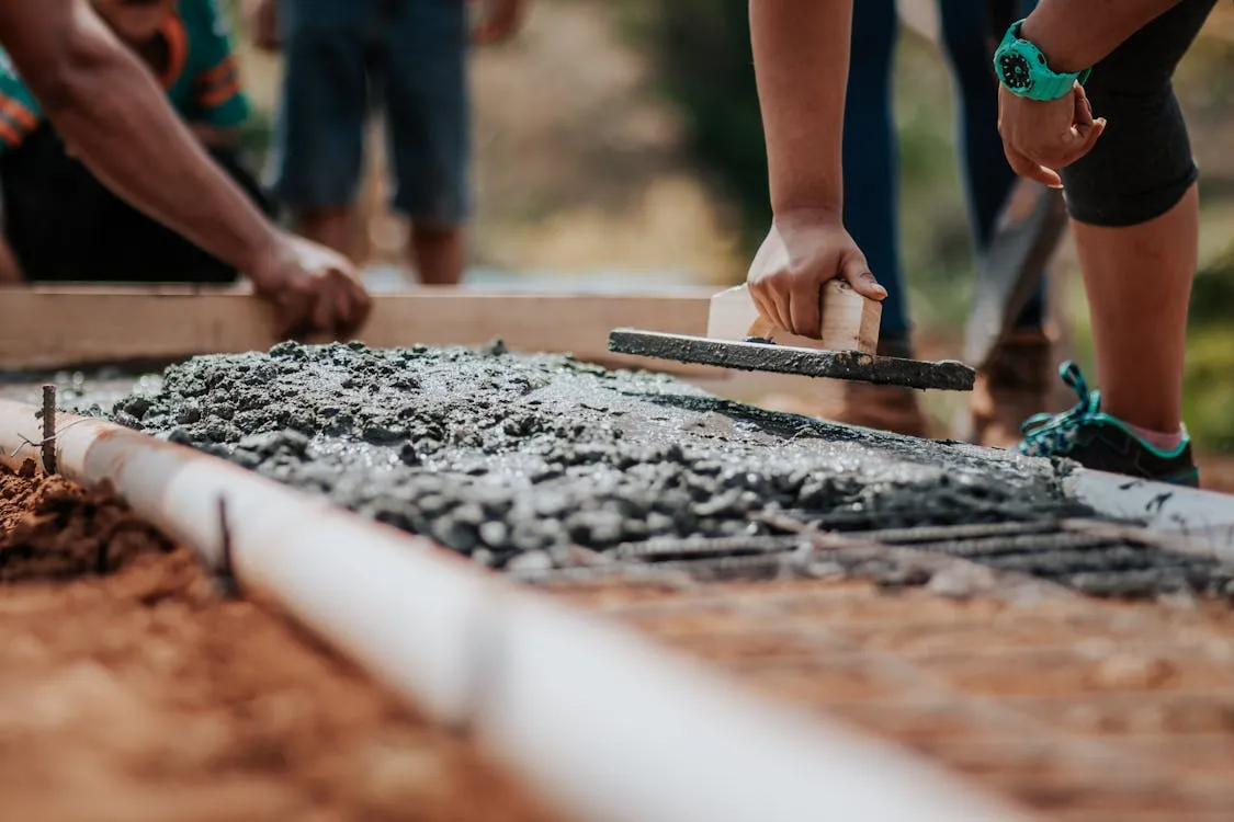 Free Construction workers leveling fresh cement on a sunny day at an outdoor site. Stock Photo