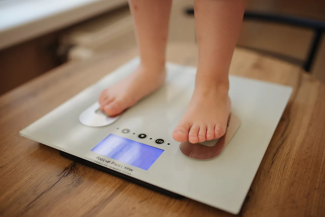 Girl_stands_and_weighs_himself_on_white_modern_electronic_smart_scale_-_51258015258.jpg