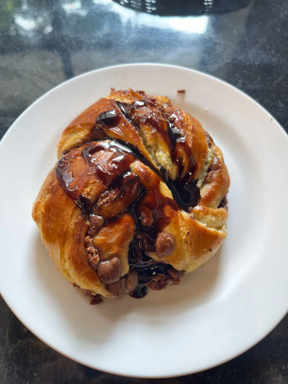 a type of croissant with chocolate chips in it and some chocolate syrup on top