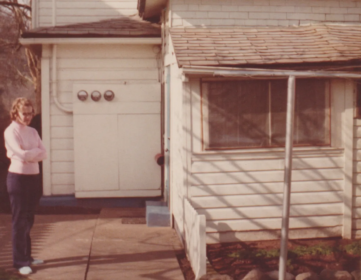1974-02 - Marilyn in a pink shirt, black pants, near a house, developed in February of that year, 1pic.png