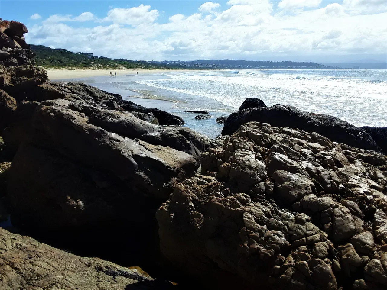 At the foot of the peninsula in the still corner at the start of the beach