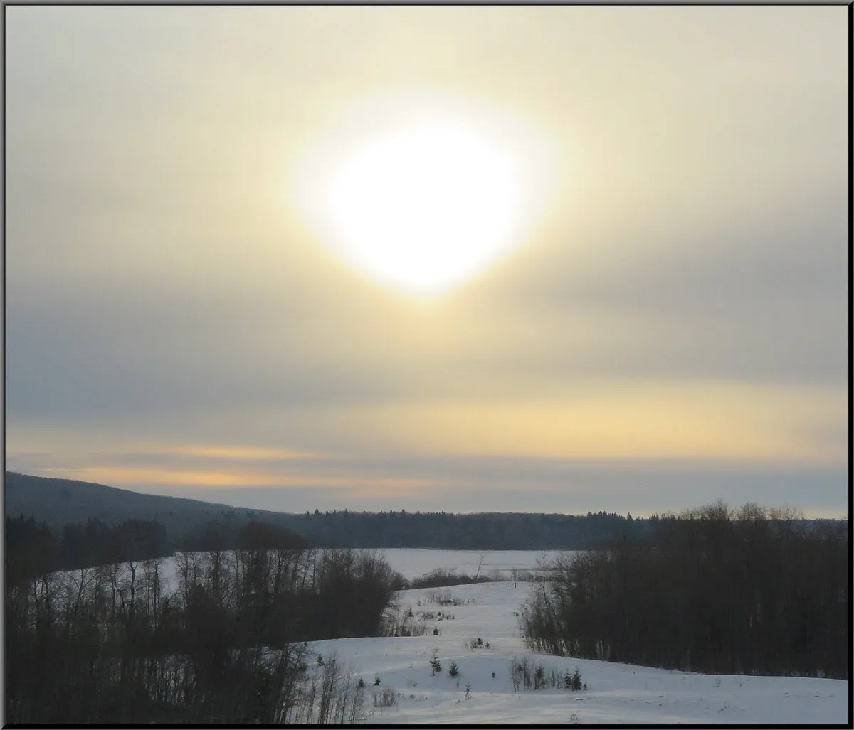 clouded sun in sky snowy trail to frozen lake.JPG