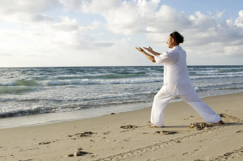 man-dressed-in-white-praticing-tai-chi-on-beasch.jpg