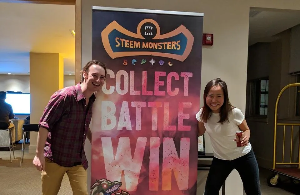 dhimmel and trang in front of steemmonsters banner jpg