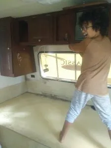 Young child using hammer to smash cabinet in RV renovation