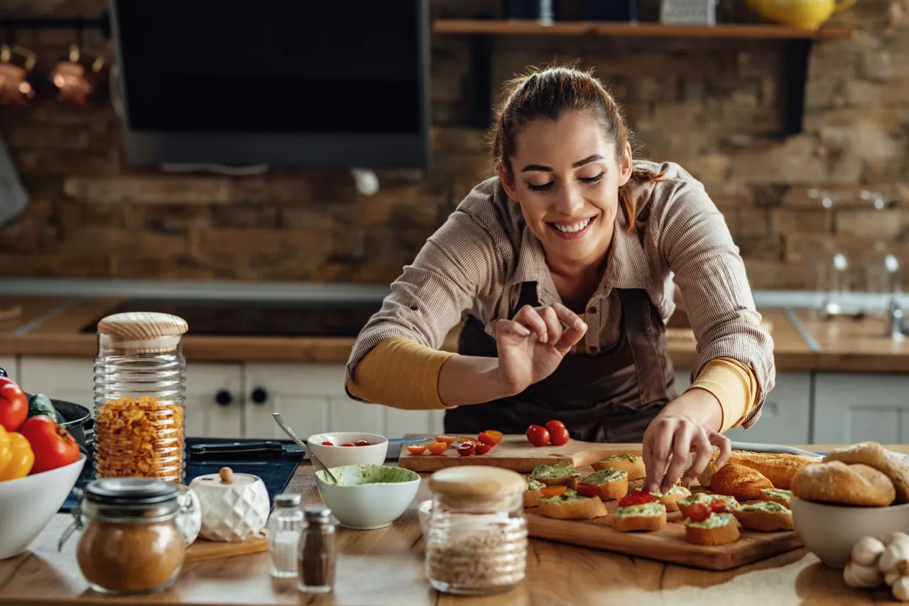 mujer-sonriente-joven-haciendo-bruschetta-ingredientes-saludables-mientras-prepara-comida-cocina.jpg