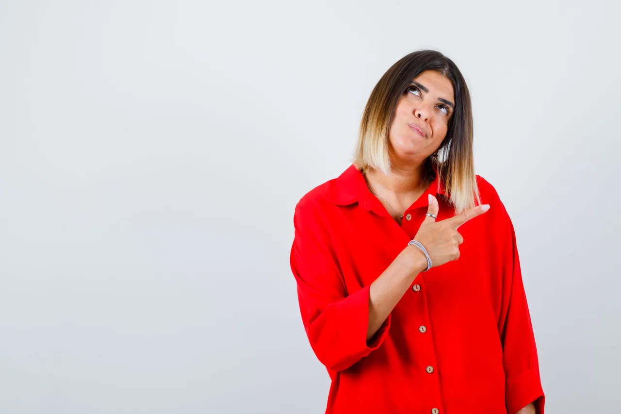 portrait-beautiful-woman-pointing-right-looking-up-red-blouse-looking-thoughtful-front-view.jpg