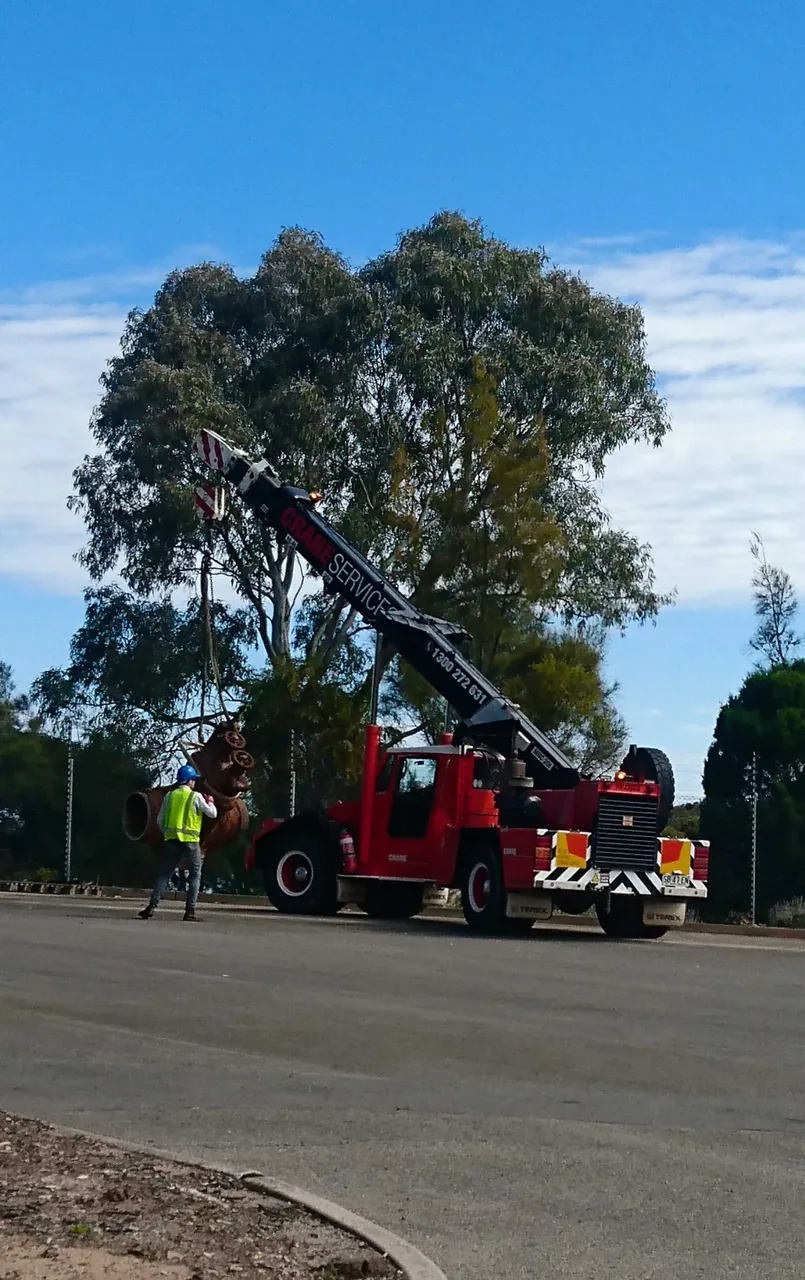 A franna crane truck setting down an old, rusty valve