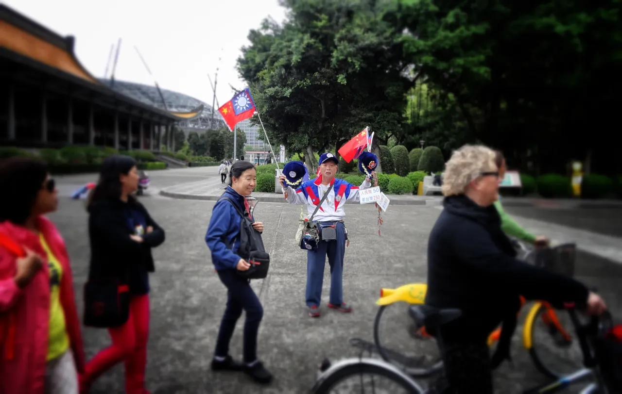 A follower of CKS sells flags and caps