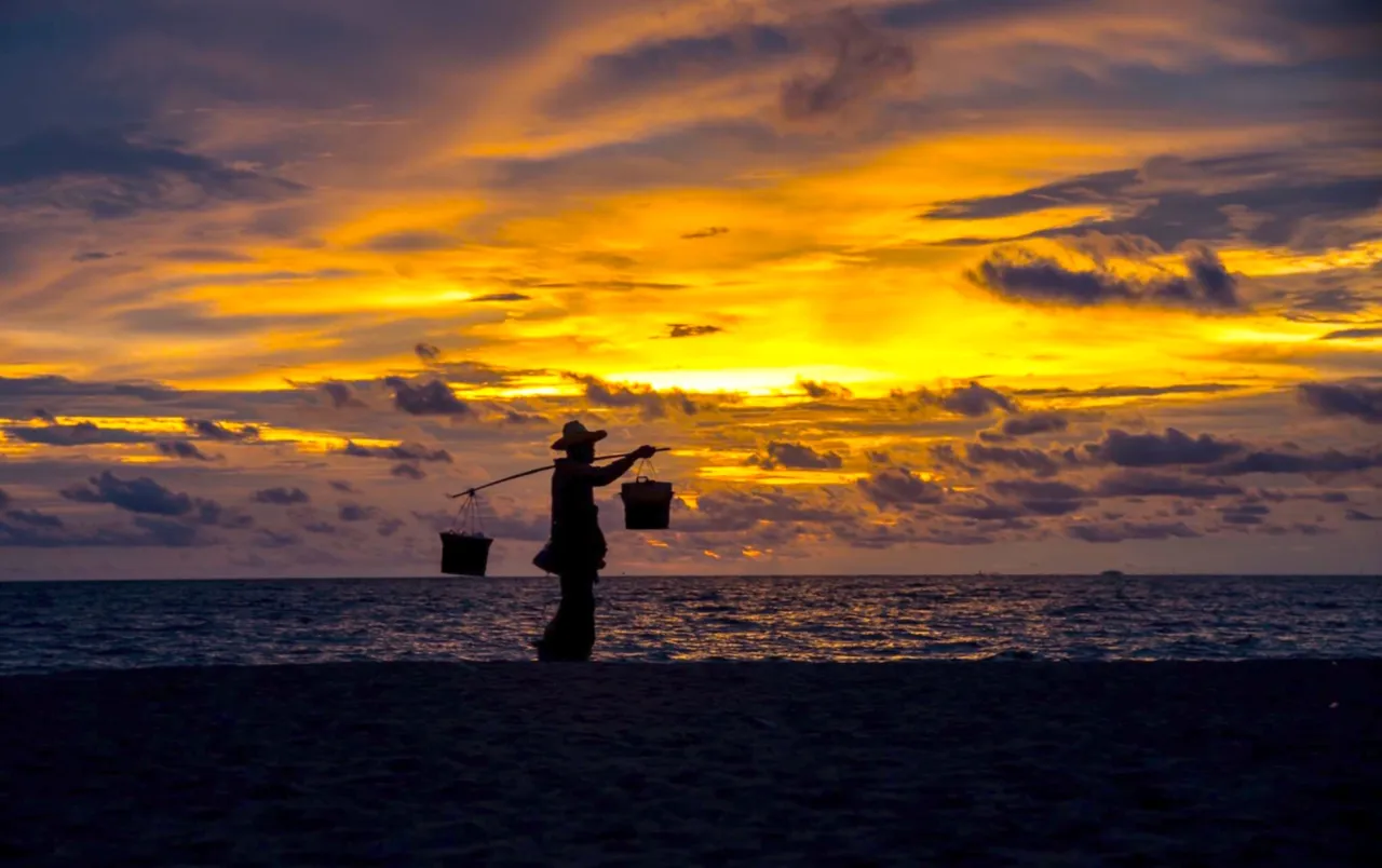 I love the above silohette photo of a man carrying supplies to sell on the beach. The sunset adds to the drama.
