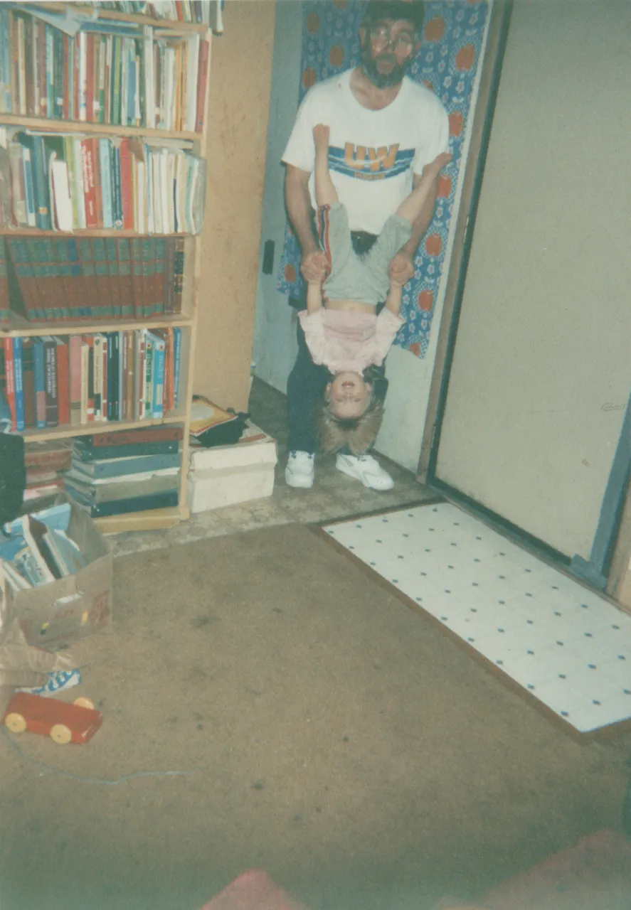 1992-11 - Dad holding Crystal upside down, 163 hallway near living room and front door.png