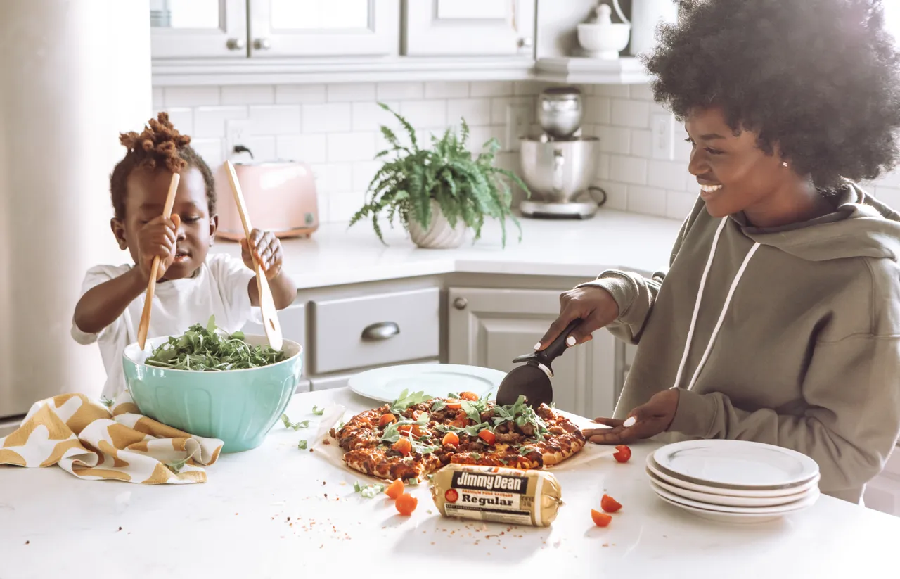 woman in white long sleeve shirt slicing pizza