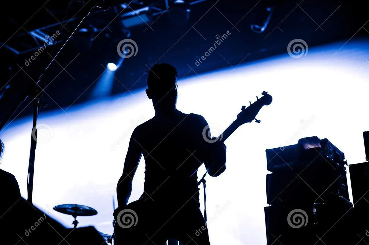 rock_band_performs_stage_guitarist_plays_solo_silhouette_guitar_player_action_front_concert_crowd_close_behind_lights_107205674.jpg