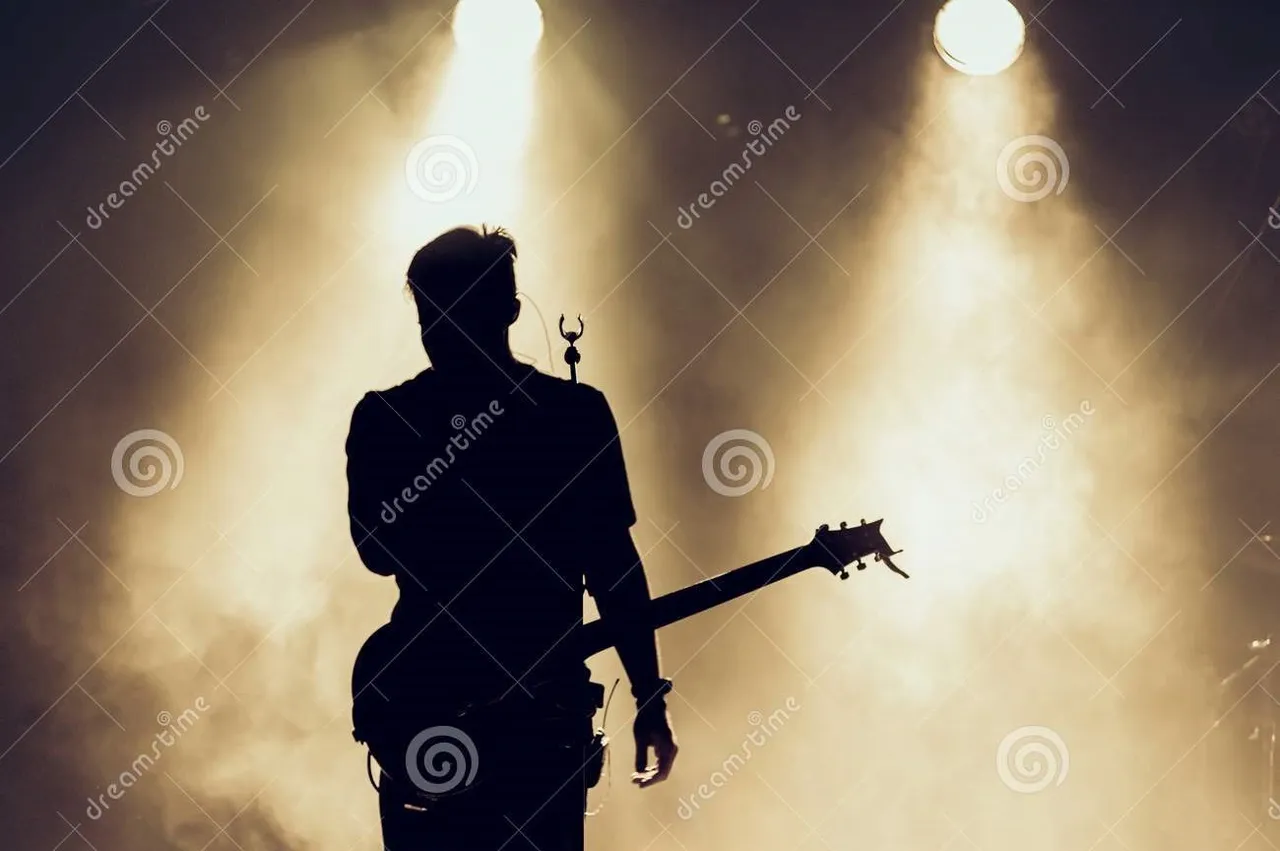 rock_band_performs_stage_guitarist_plays_solo_silhouette_guitar_player_action_front_concert_crowd_close_behind_lights_106348233.jpg