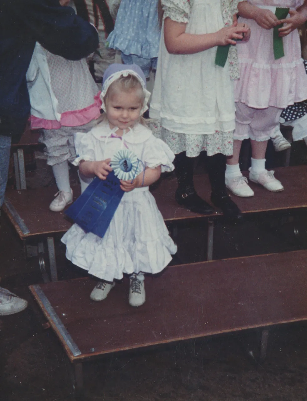 1990s - Crystal or Katie in the 1980s - Looks like Crystal and little bit like Katie, a girl winning a blue ribbon, other random kids ona  stage-4.png