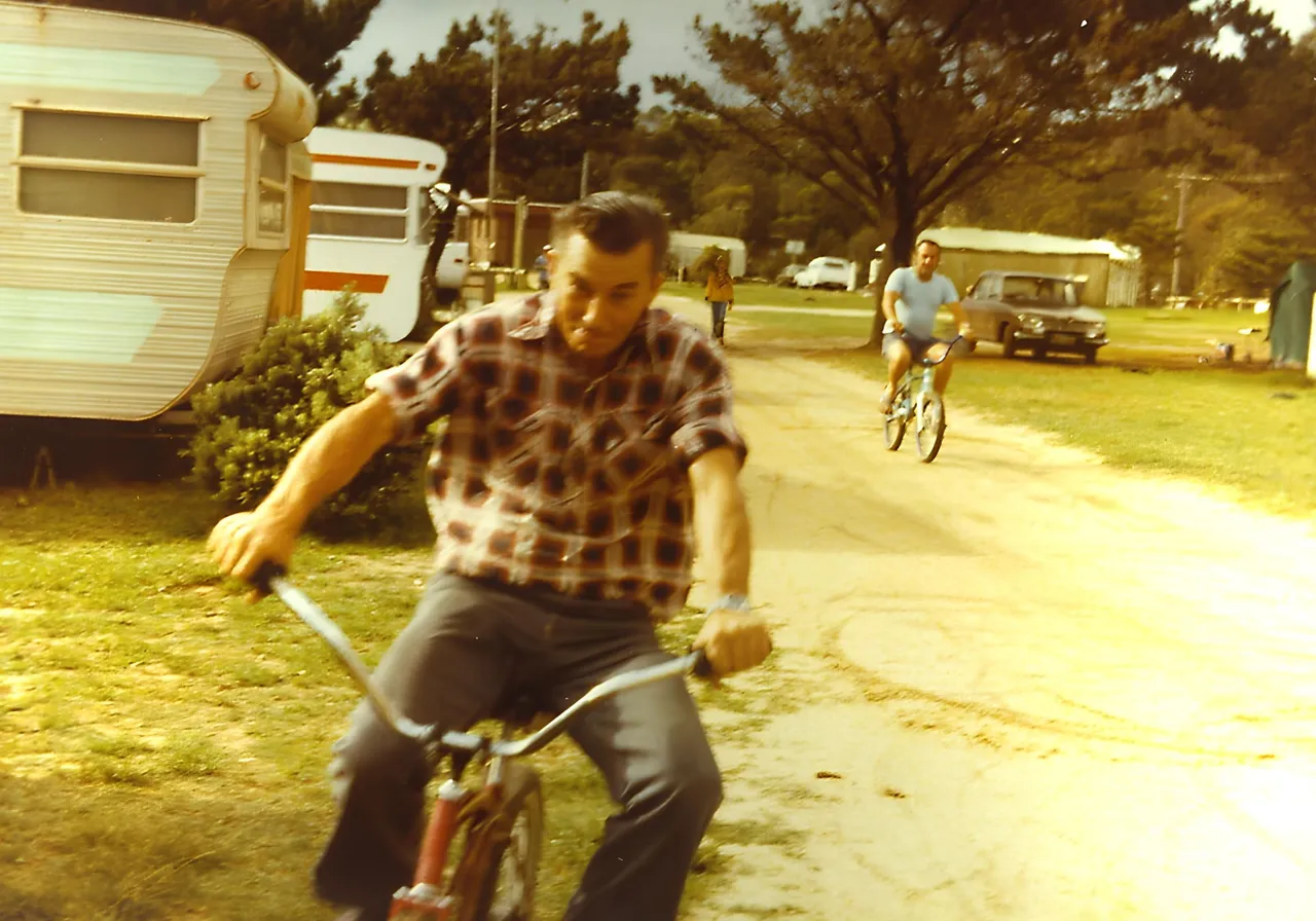 DAD AND DOUCHY RACING ON KIDS BIKES AT TATHRA CARAVAN PARK.png