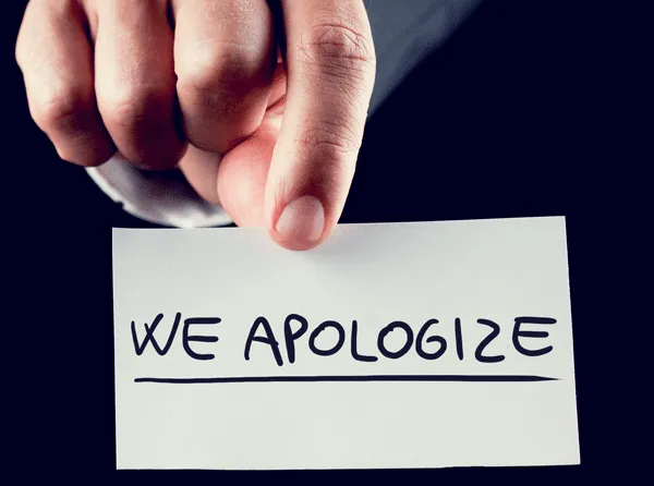 Business-man-holding-a-we-apologize-sign-Featured.png