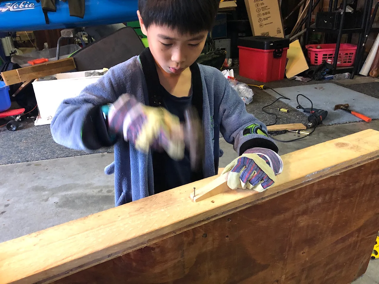 Thien-San is hammering a board to build his workbench