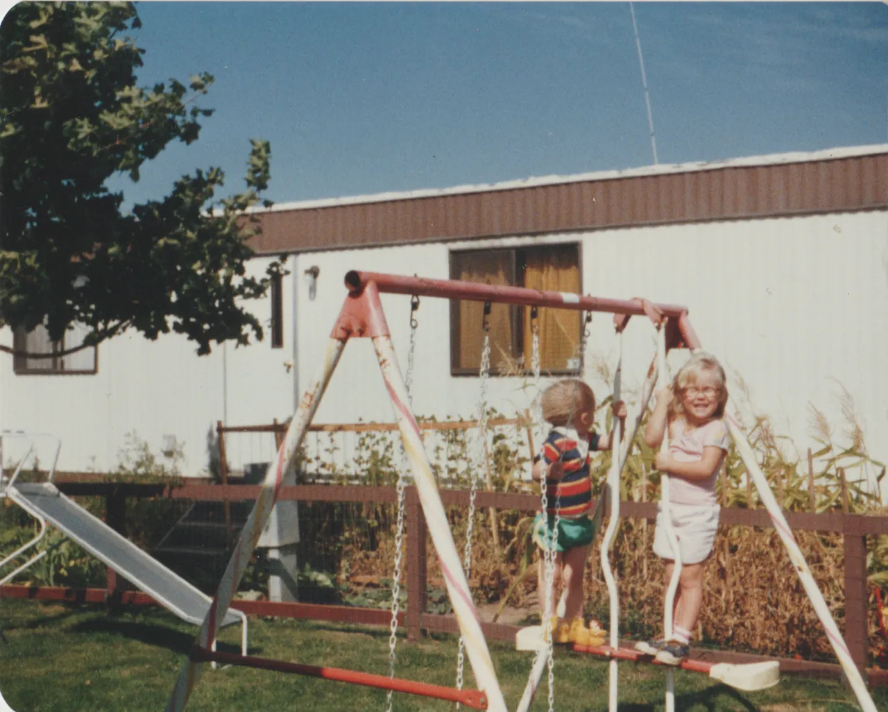 1984 - Summer - Rick with short hair, Katie, on a swing, could be 1983 because Rick has short hair, front yard, swingset.png