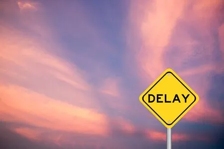 147779947-yellow-color-transportation-sign-with-word-delay-on-violet-cloud-sky-background.jpg