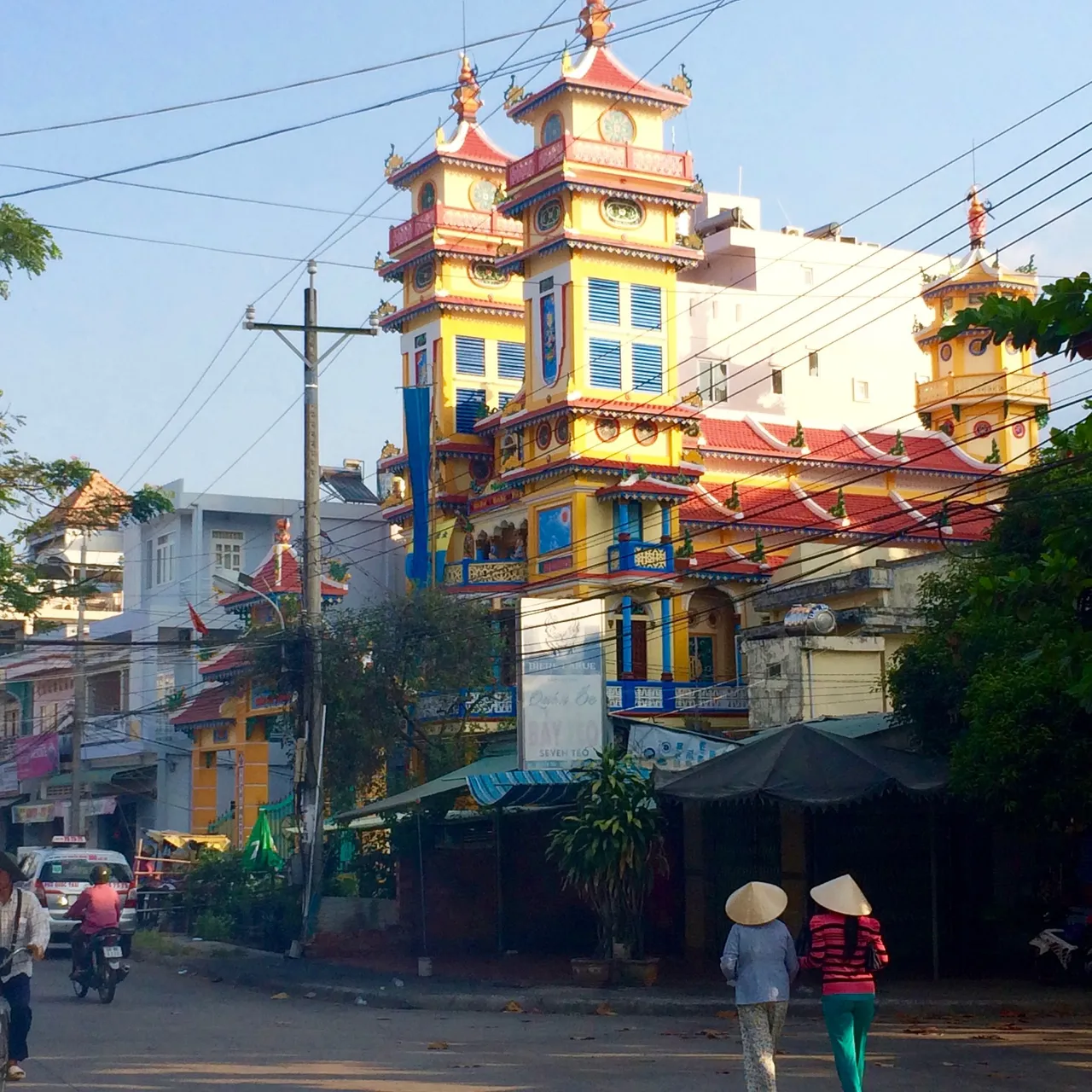 6 Two ladies wearing traditional Vietnamese Non La hats walk past the temple .jpg