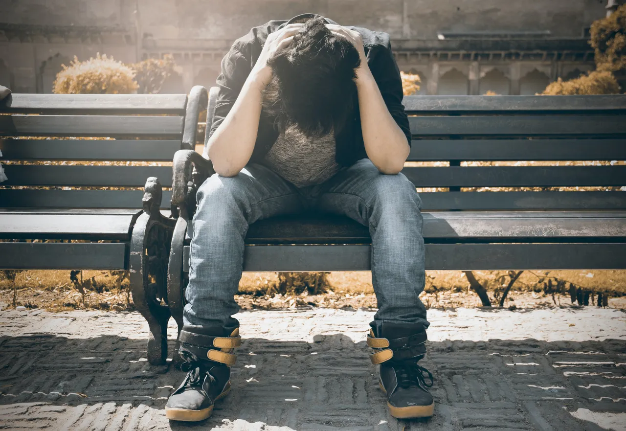 man-in-black-shirt-and-gray-denim-pants-sitting-on-gray-1134204.jpg