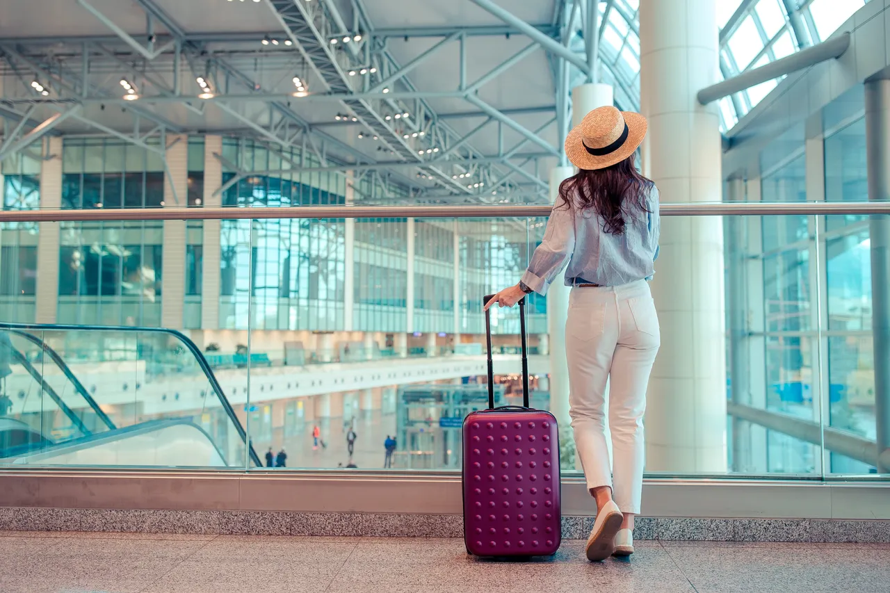 young-woman-in-hat-with-baggage-in-international-a-2021-08-30-02-32-33-utc.jpg